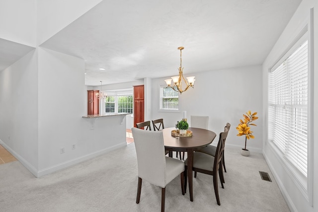 dining space featuring a chandelier, baseboards, and light carpet