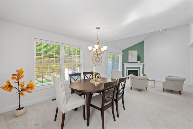 dining area featuring light carpet, a chandelier, baseboards, a glass covered fireplace, and lofted ceiling
