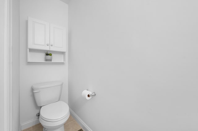 bathroom featuring baseboards, tile patterned flooring, and toilet