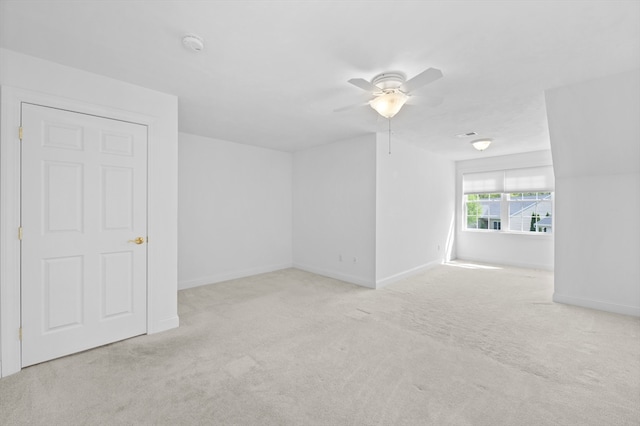 empty room with carpet floors, ceiling fan, baseboards, and a smoke detector