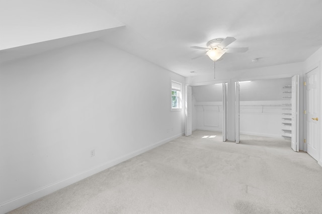 unfurnished bedroom with carpet flooring, two closets, baseboards, and a ceiling fan