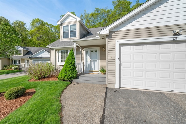 view of front of property with asphalt driveway, a garage, and a front yard
