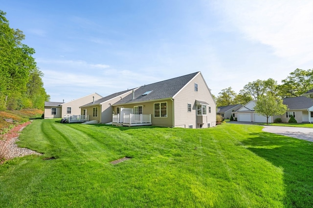 back of property featuring a yard, a deck, and a detached garage