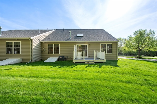 back of property featuring a deck, a yard, and roof with shingles