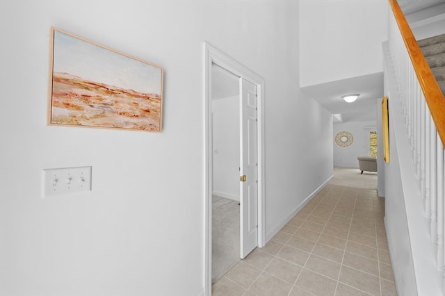 hall featuring stairway, light tile patterned floors, and baseboards