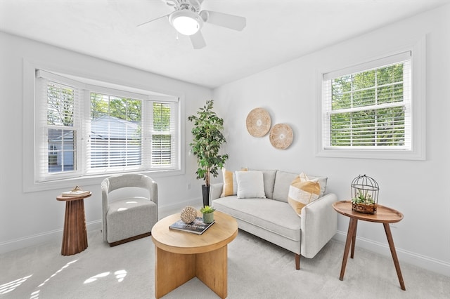 living area with healthy amount of natural light, baseboards, and light carpet
