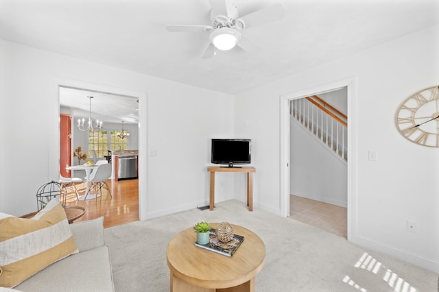 living room featuring stairs, a chandelier, light colored carpet, and ceiling fan