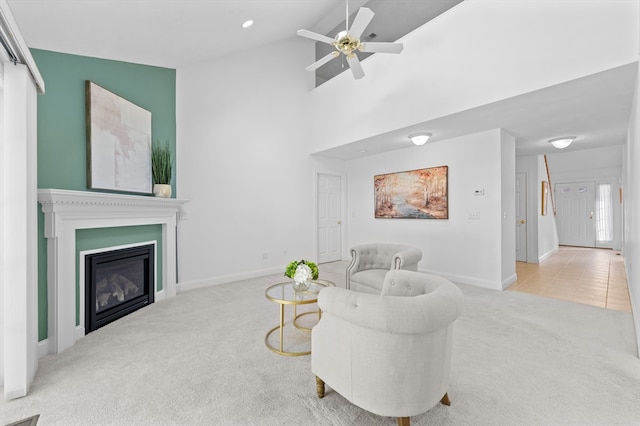 carpeted living room featuring a ceiling fan, baseboards, a glass covered fireplace, high vaulted ceiling, and recessed lighting