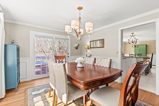 dining room with a chandelier, light wood finished floors, and wainscoting