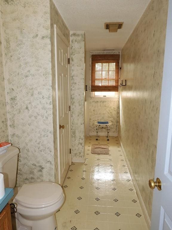 12C Oliver St Unit 12C, Haverhill, MA 01832 - bathroom featuring wallpapered walls, toilet, vanity, a textured ceiling, and baseboards