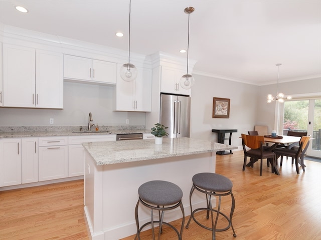 kitchen with stainless steel appliances, a center island, sink, and white cabinetry