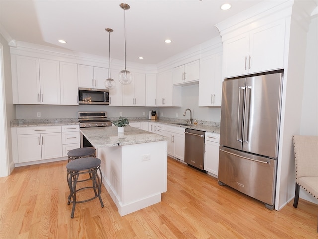 kitchen with light hardwood / wood-style flooring, stainless steel appliances, pendant lighting, and a center island