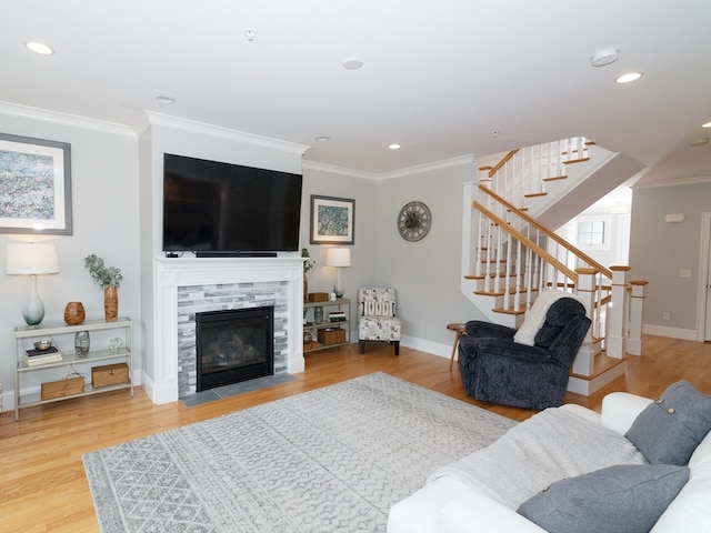 living room with a stone fireplace, hardwood / wood-style flooring, and ornamental molding