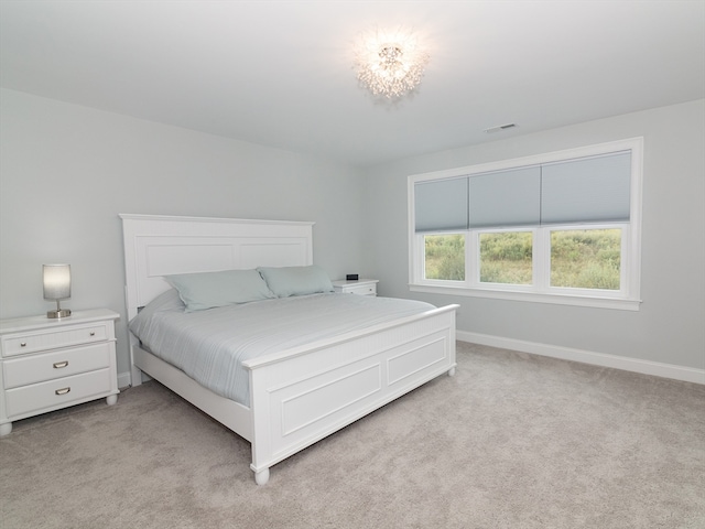 bedroom featuring light carpet and a notable chandelier