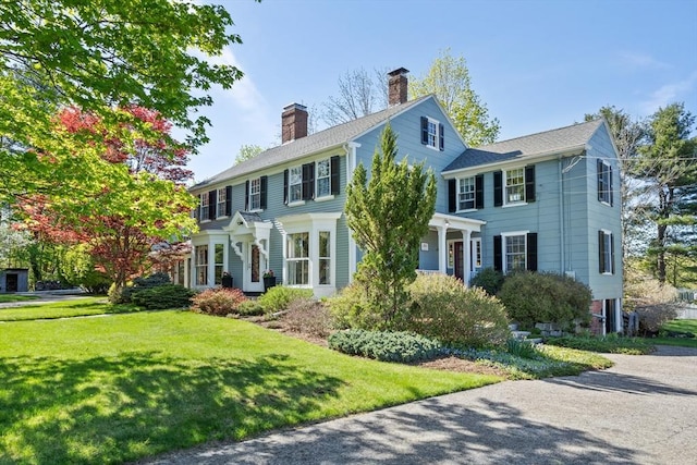 colonial house featuring a front yard and a chimney