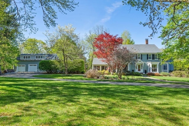 view of front of home with an attached garage, a front yard, driveway, and a chimney