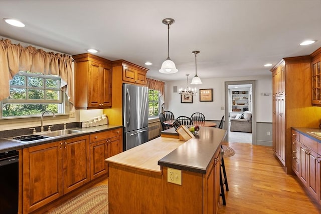 kitchen featuring freestanding refrigerator, a sink, dishwasher, a kitchen island, and brown cabinets