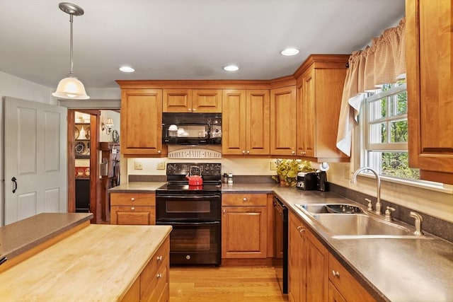 kitchen featuring black appliances, a sink, brown cabinets, hanging light fixtures, and recessed lighting