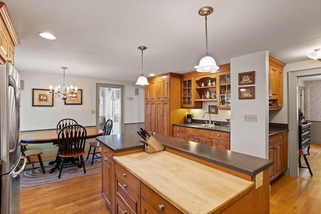 kitchen featuring freestanding refrigerator, a sink, light wood finished floors, a kitchen island, and recessed lighting
