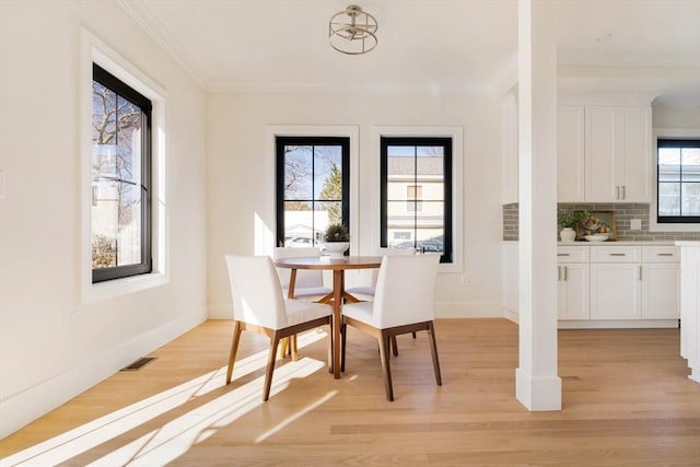 dining area with crown molding and light hardwood / wood-style flooring