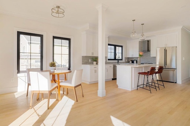 kitchen featuring pendant lighting, light hardwood / wood-style floors, appliances with stainless steel finishes, a kitchen island, and white cabinetry