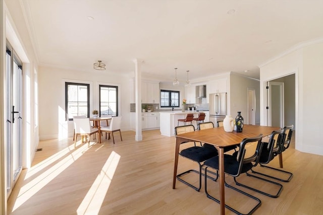 dining space with light hardwood / wood-style floors and ornamental molding