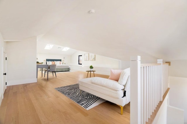 living area with light hardwood / wood-style floors and vaulted ceiling with skylight