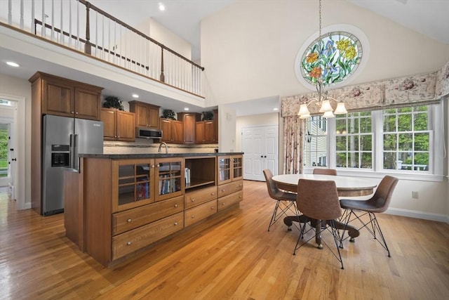 dining area featuring high vaulted ceiling, baseboards, light wood-type flooring, and a chandelier