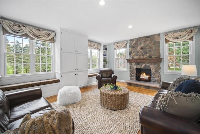living area featuring light wood-style flooring, a stone fireplace, and recessed lighting
