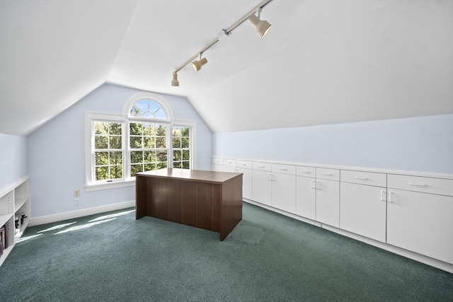 unfurnished office with rail lighting, lofted ceiling, dark carpet, and baseboards