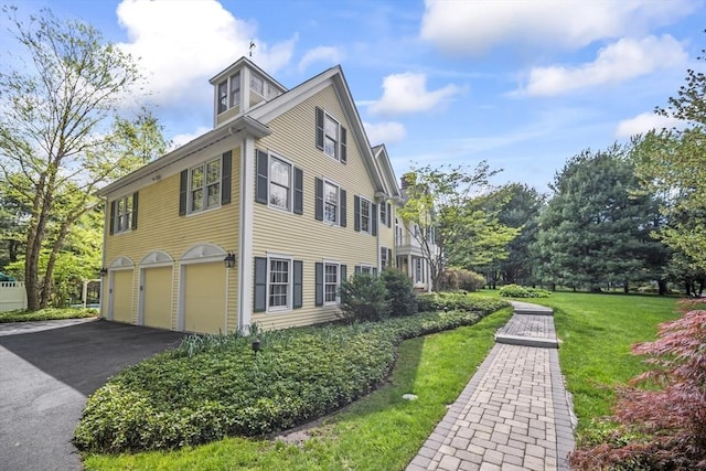 view of side of home with an attached garage, driveway, and a lawn