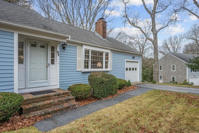 view of exterior entry with a garage and a yard