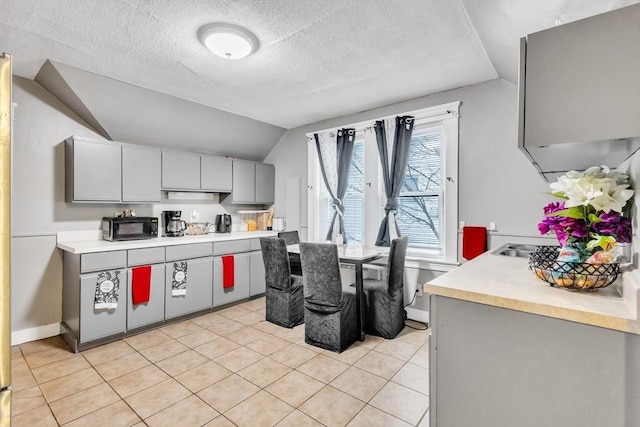 38 Cliff St, Fitchburg, MA 01420 - kitchen with black microwave, gray cabinetry, light tile patterned flooring, vaulted ceiling, and light countertops