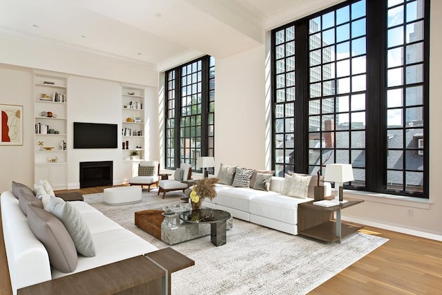 living room with crown molding, hardwood / wood-style floors, and built in features