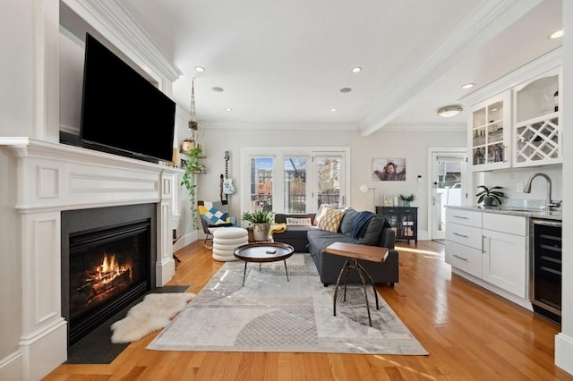 living room with light wood-type flooring, ornamental molding, indoor wet bar, and wine cooler