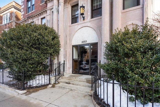 entrance to property featuring fence and brick siding