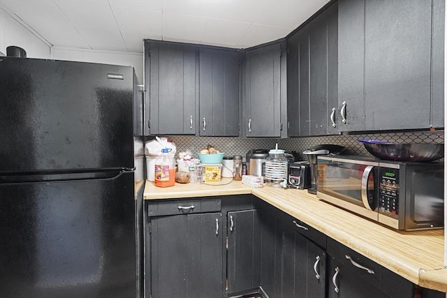 19 Chester St, Fitchburg, MA 01420 - kitchen with freestanding refrigerator, stainless steel microwave, light countertops, dark cabinets, and decorative backsplash