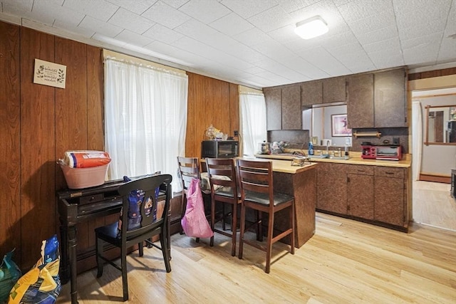 19 Chester St, Fitchburg, MA 01420 - kitchen with light wood-type flooring, light countertops, a kitchen breakfast bar, wooden walls, and a peninsula