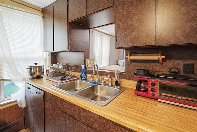 19 Chester St, Fitchburg, MA 01420 - kitchen with a sink, a baseboard heating unit, light countertops, and dark brown cabinetry