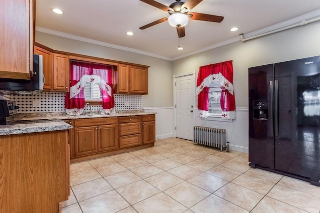 67 Alexander St, Springfield, MA 01107 - kitchen featuring black fridge, radiator heating unit, ceiling fan, brown cabinets, and decorative backsplash