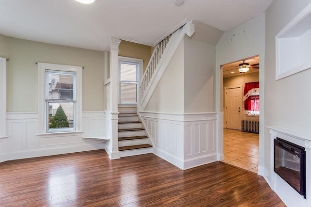 67 Alexander St, Springfield, MA 01107 - stairway with radiator heating unit, a wainscoted wall, wood finished floors, a ceiling fan, and a glass covered fireplace