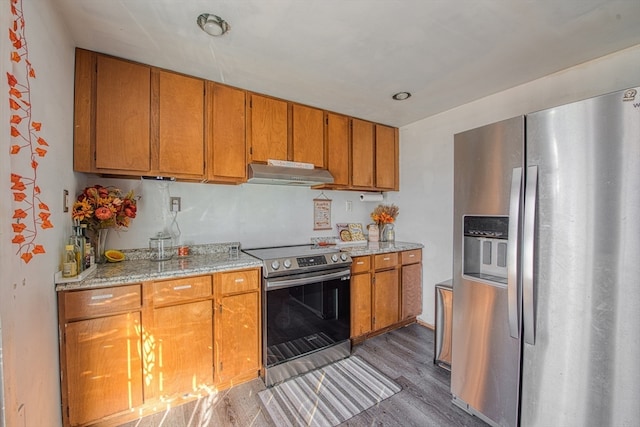 kitchen featuring hardwood / wood-style flooring, light stone countertops, and stainless steel appliances