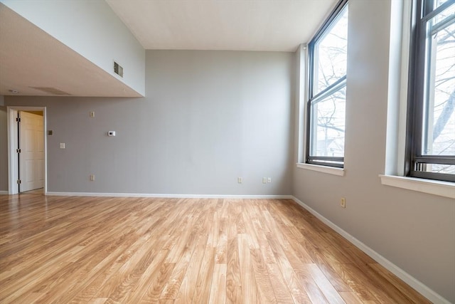 empty room featuring visible vents, light wood-style flooring, and baseboards