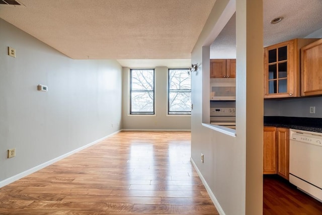 kitchen featuring a textured ceiling, wood finished floors, white appliances, and glass insert cabinets