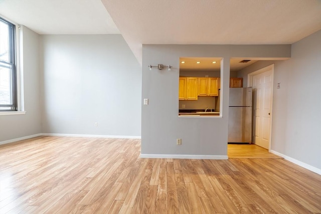unfurnished living room with light wood finished floors and baseboards