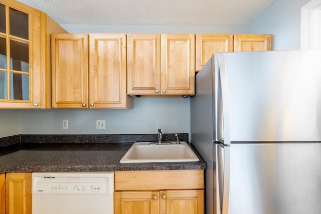 kitchen featuring light brown cabinets, freestanding refrigerator, a sink, and dishwasher