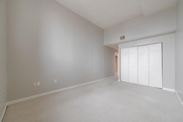 unfurnished bedroom featuring baseboards, a closet, carpet floors, visible vents, and high vaulted ceiling