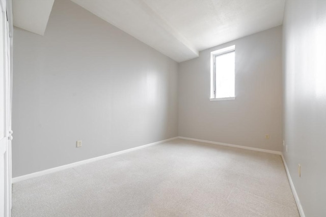 unfurnished room with baseboards, light colored carpet, and lofted ceiling