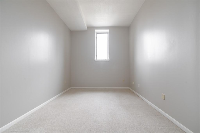 unfurnished room featuring light colored carpet and baseboards