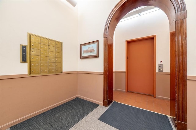 hallway featuring arched walkways, baseboards, and carpet